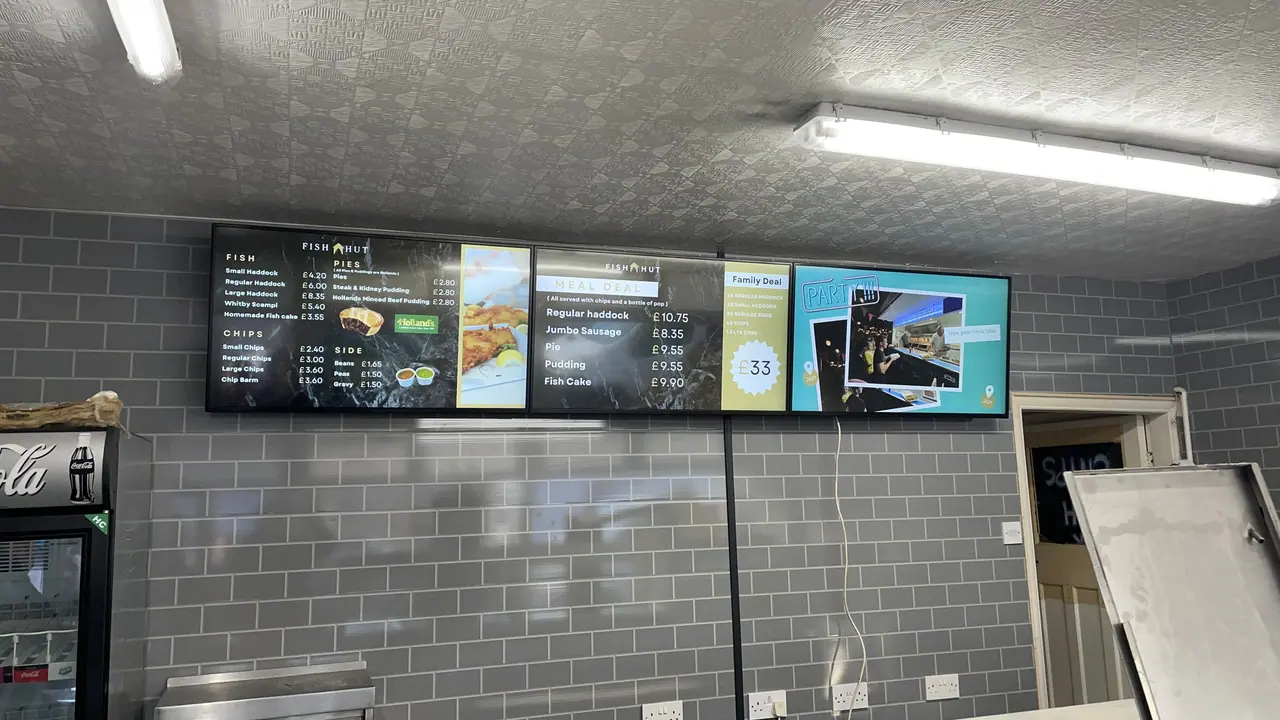 Three-screen digital menu board above a takeaway counter
