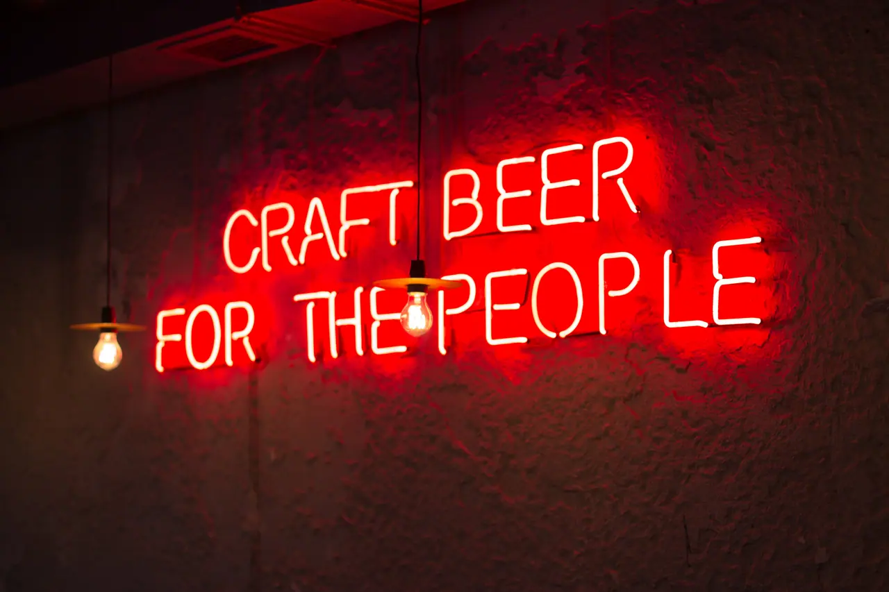 Red neon sign reading CRAFT BEER FOR THE PEOPLE on a wall